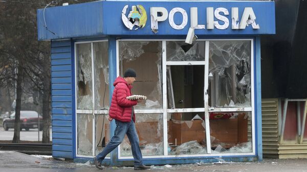 Мужчина проходит мимо разрушенного здания полицейского поста в Алма-Ате