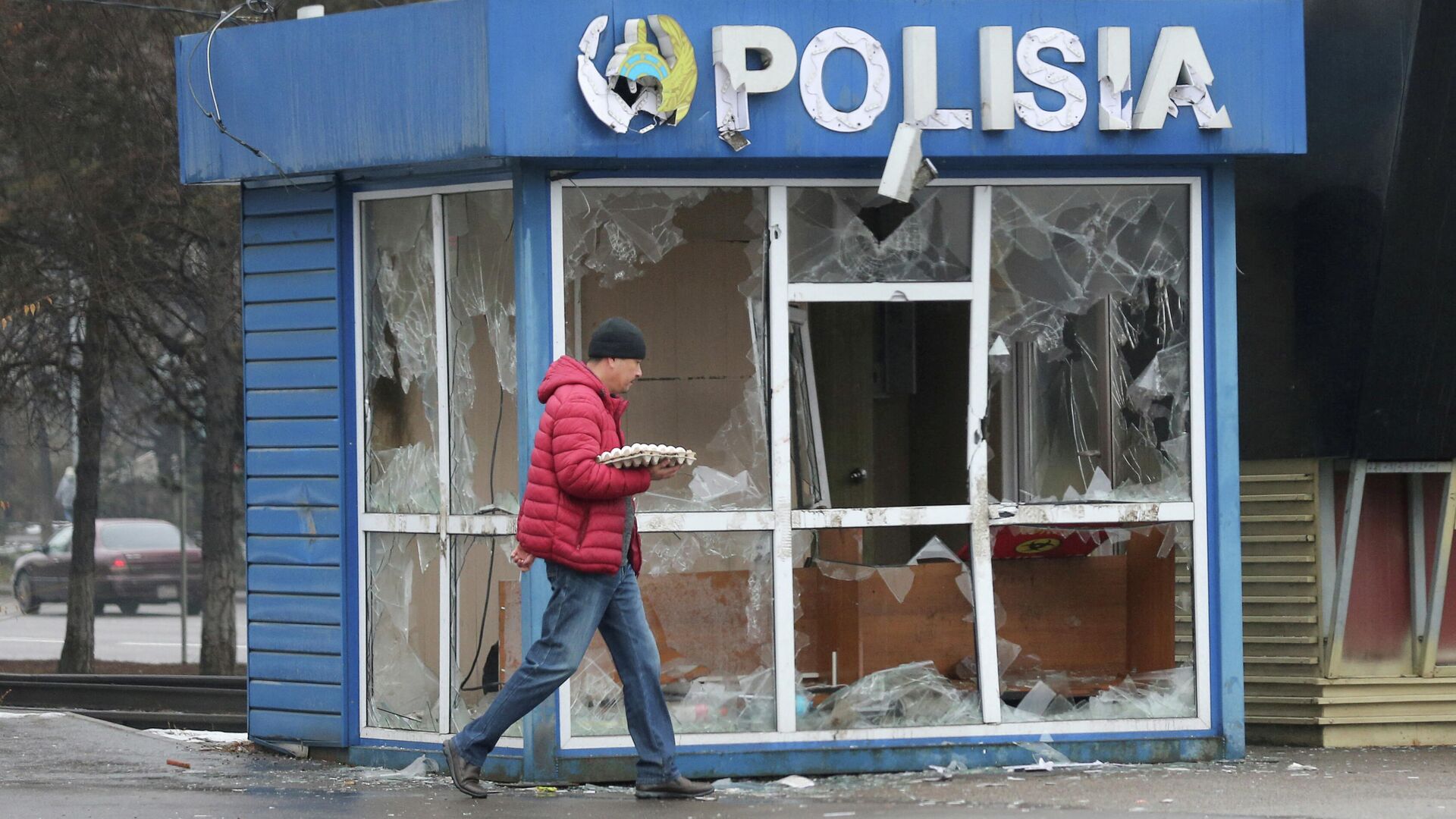 Мужчина проходит мимо разрушенного здания полицейского поста в Алма-Ате - РИА Новости, 1920, 14.01.2022