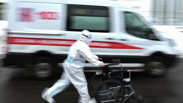 Медицинский работник возле автомобиля скорой помощи на территории городской клинической больницы № 40 в Коммунарке