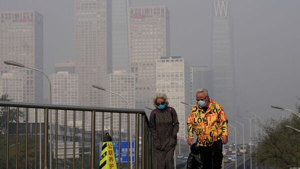 Пожилая пара в масках идет по подвесному мосту в центральном деловом районе в Пекине