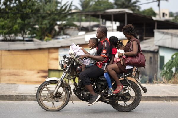 Семья едет на мотоцикле в Дуале