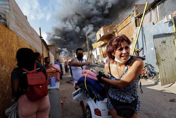 Жители бегут со своими вещами во время пожара в районе Лагуна-Верде в Икике, Чили