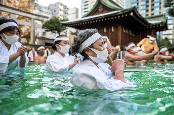 Верующие во время традиционного купания в холодной воде во дворе храма Teppozu Inari в Токио