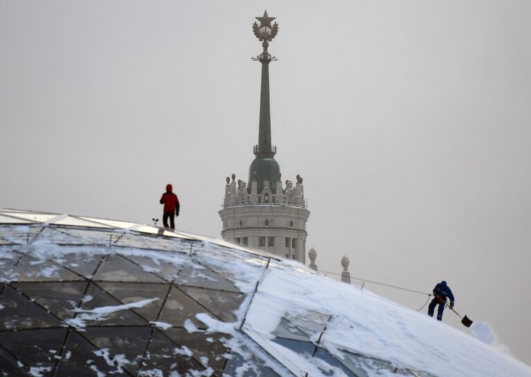 Сотрудники коммунальной службы чистят снег в парке Зарядье в Москве