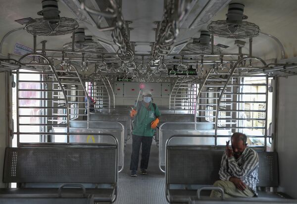 Сотрудник железной дороги распыляет дезинфицирующее средство против коронавируса в Хайдарабаде, Индия
