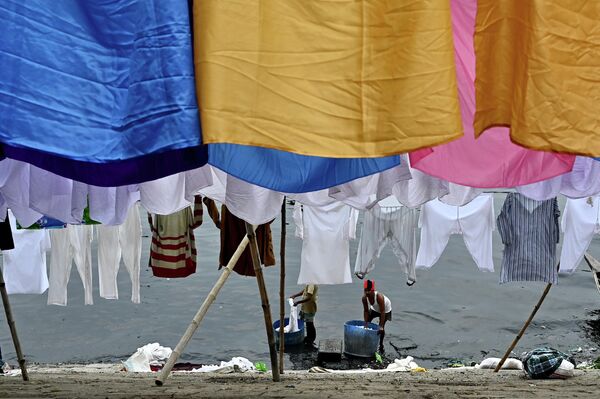 Рабочие развешивают чистую одежду вдоль берега реки Буриганга в Дакке, Бангладеш 