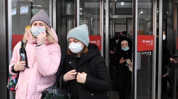 Люди в медицинских масках выходят из вестибюля одной из станций Московского метрополитена