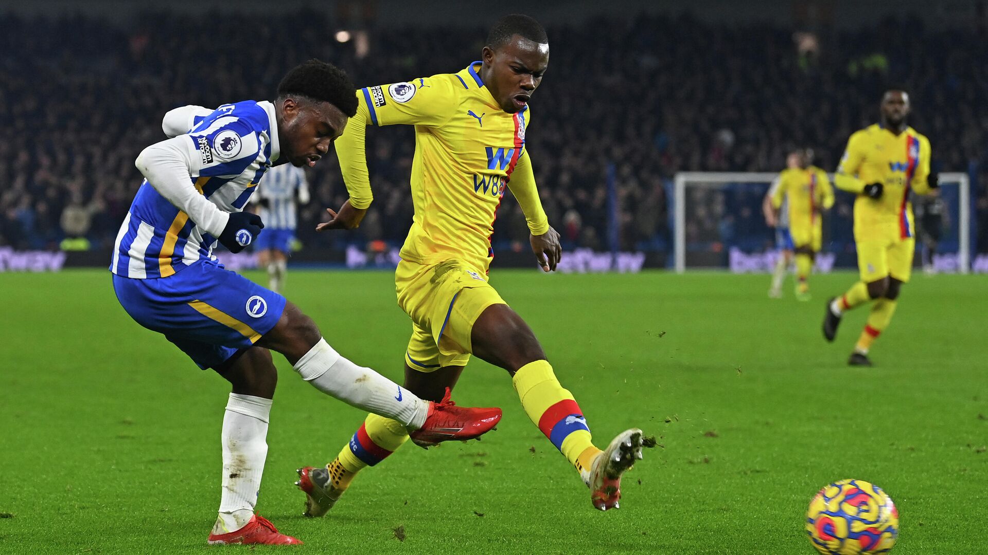 Brighton's English midfielder Tariq Lamptey (L) crosses the ball in front of Crystal Palace's English defender Tyrick Mitchell (C) during the English Premier League football match between Brighton and Hove Albion and Crystal Palace at the American Express Community Stadium in Brighton, southern England on January 14, 2022. - The game ended 1-1. (Photo by Glyn KIRK / AFP) / RESTRICTED TO EDITORIAL USE. No use with unauthorized audio, video, data, fixture lists, club/league logos or 'live' services. Online in-match use limited to 120 images. An additional 40 images may be used in extra time. No video emulation. Social media in-match use limited to 120 images. An additional 40 images may be used in extra time. No use in betting publications, games or single club/league/player publications. /  - РИА Новости, 1920, 15.01.2022