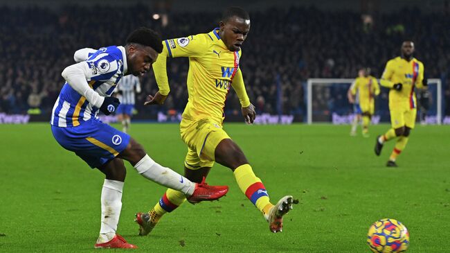 Brighton's English midfielder Tariq Lamptey (L) crosses the ball in front of Crystal Palace's English defender Tyrick Mitchell (C) during the English Premier League football match between Brighton and Hove Albion and Crystal Palace at the American Express Community Stadium in Brighton, southern England on January 14, 2022. - The game ended 1-1. (Photo by Glyn KIRK / AFP) / RESTRICTED TO EDITORIAL USE. No use with unauthorized audio, video, data, fixture lists, club/league logos or 'live' services. Online in-match use limited to 120 images. An additional 40 images may be used in extra time. No video emulation. Social media in-match use limited to 120 images. An additional 40 images may be used in extra time. No use in betting publications, games or single club/league/player publications. / 