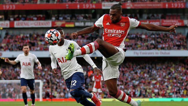 Arsenal's Portuguese defender Nuno Tavares (R) crosses the ball during the English Premier League football match between Arsenal and Tottenham Hotspur at the Emirates Stadium in London on September 26, 2021. (Photo by Ian KINGTON / IKIMAGES / AFP) / RESTRICTED TO EDITORIAL USE. No use with unauthorized audio, video, data, fixture lists, club/league logos or 'live' services. Online in-match use limited to 45 images, no video emulation. No use in betting, games or single club/league/player publications.