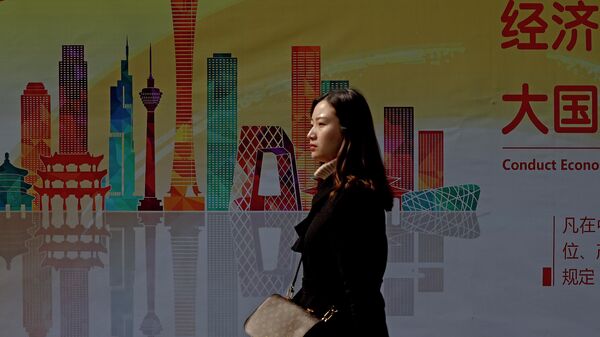 Женщина проходит мимо рекламного щита с изображением небоскребов в центральном деловом районе Пекина