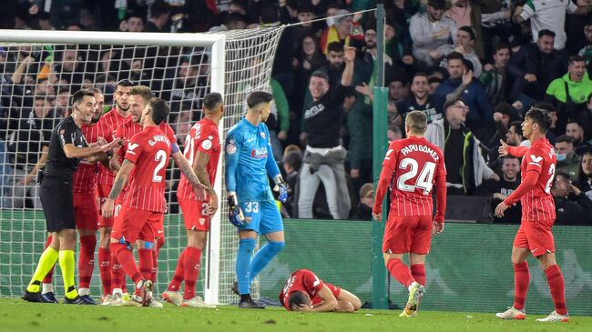 Sevilla's Spanish midfielder Joan Jordan Moreno (C) lies on the pitch after being hit by an object thrown from the tribunes during the Spanish Copa del Rey (King's Cup) round of 16 first leg football match between Real Betis and Sevilla FC at the Benito Villamarin stadium in Seville on January 15, 2022. - The Copa del Rey match between rivals Sevilla and Real Betis was stopped after Sevilla's Joan Jordan was struck on the head by an object thrown from the crowd. (Photo by CRISTINA QUICLER / AFP)