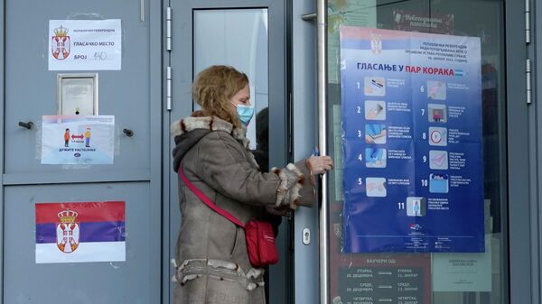 Женщина заходит на избирательный участок в Белграде для голосования на референдуме по изменениям конституции Сербии