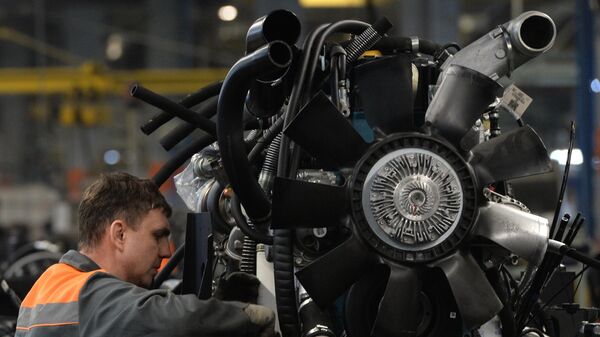 Рабочий собирает двигатель на автомобильном заводе 