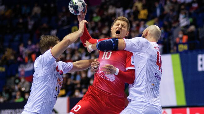 Russia's Valentin Vorobev (C) is blocked during the Men's European Handball Championship preliminary round Group F match between Slovakia and Russia in Kosice, Slovakia on January 17, 2022. (Photo by PETER LAZAR / AFP)