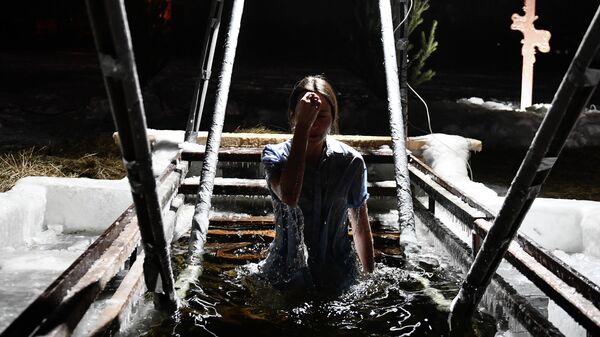 Девушка окунается в купель на Верх-Исетском пруду в Екатеринбурге во время празднования Крещения