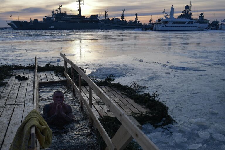 Мужчина окунается в купель в Средней гавани в Кронштадте во время празднования Крещения