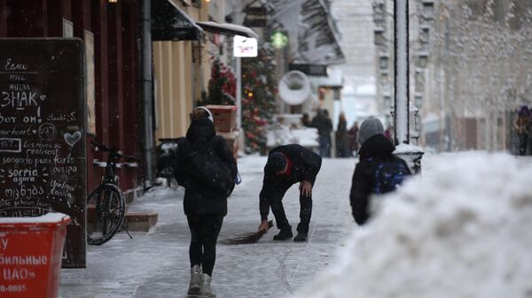 Мужчина убирает снег на одной из улиц в Москве