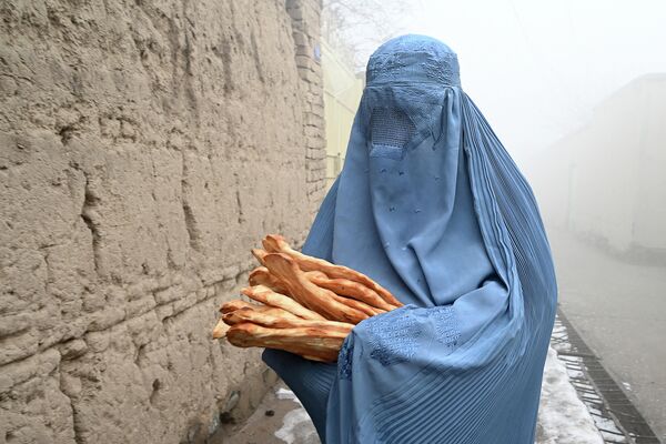 Женщина в парандже c бесплатным хлебом, который раздают в рамках кампании Спасем афганцев от голода в Кабуле. 18 января 2022 года