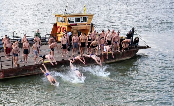 Православные христиане прыгают в ледяную реку Сава в Белграде, Сербия, чтобы отметить приближающееся Крещение.