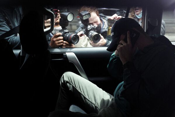Представители СМИ фотографируют неизвестного мужчину, выезжающего с автостоянки у офиса юридической команды сербского теннисиста Новака Джоковича в сопровождении полиции в Мельбурне, Австралия