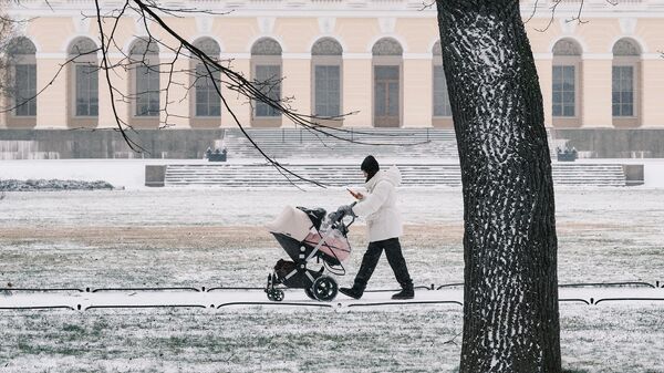 Девушка с коляской гуляет по территории Михайловского сада в Санкт-Петербурге