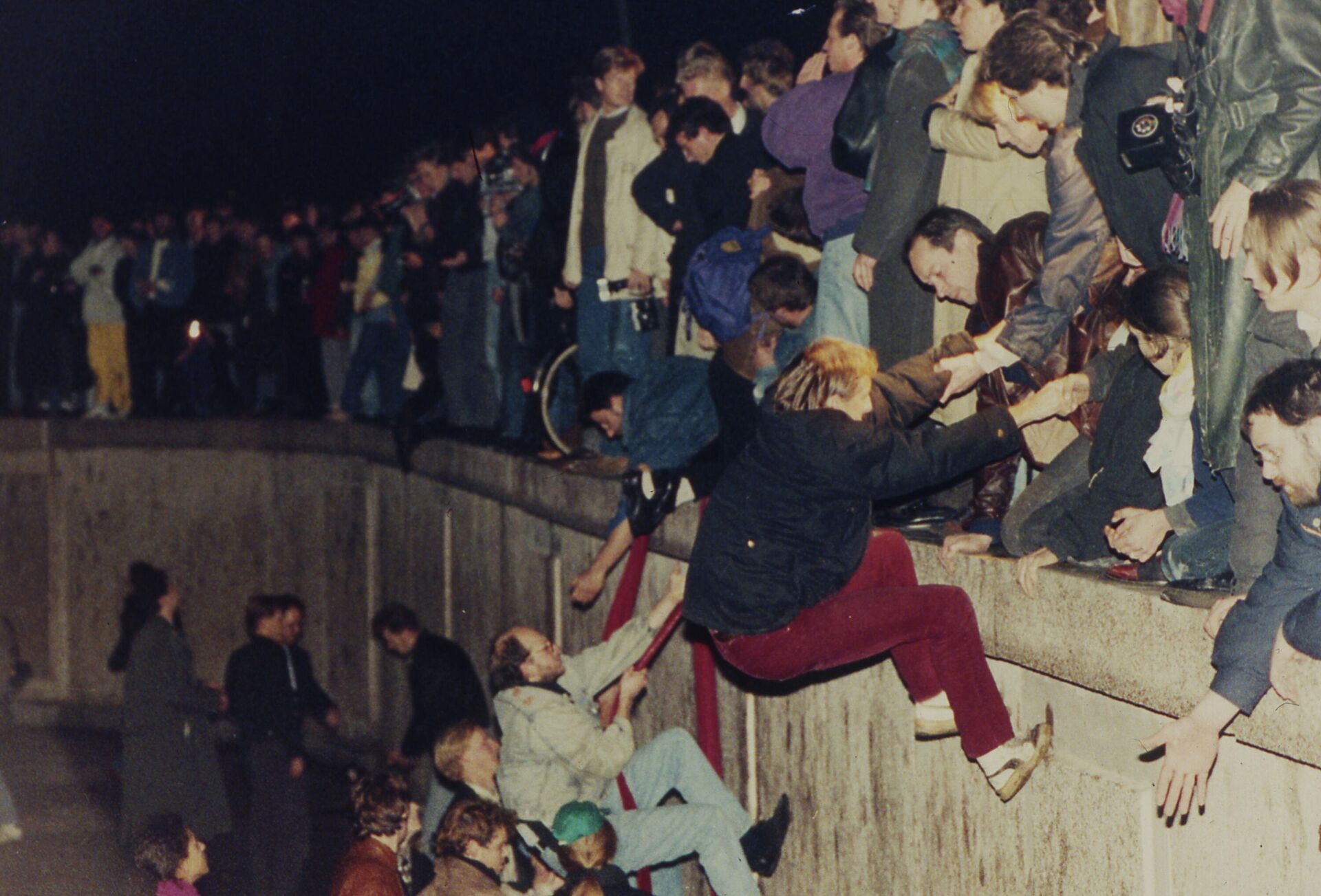 Жителям Восточного Берлина помогают жители Западного Берлина, когда они поднимаются на Берлинскую стену. - РИА Новости, 1920, 21.02.2024