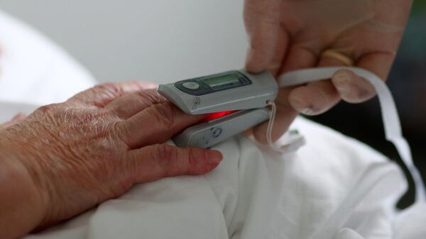Медицинский сотрудник измеряет пульсоксиметром сатурацию у пациента