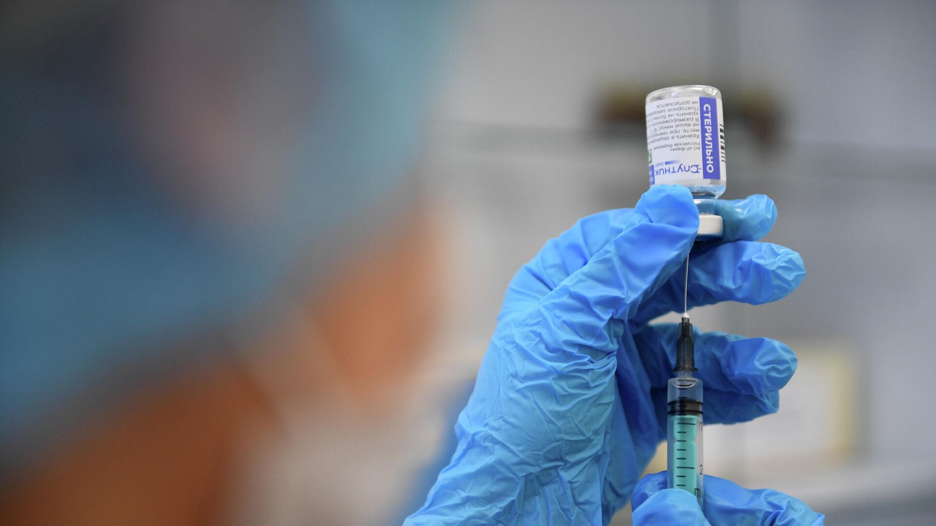 Медицинский сотрудник наполняет шприц вакциной от COVID-192