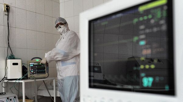 Медицинский работник настраивает прикроватный монитор в палате интенсивной терапии в красной зоне инфекционного отделения