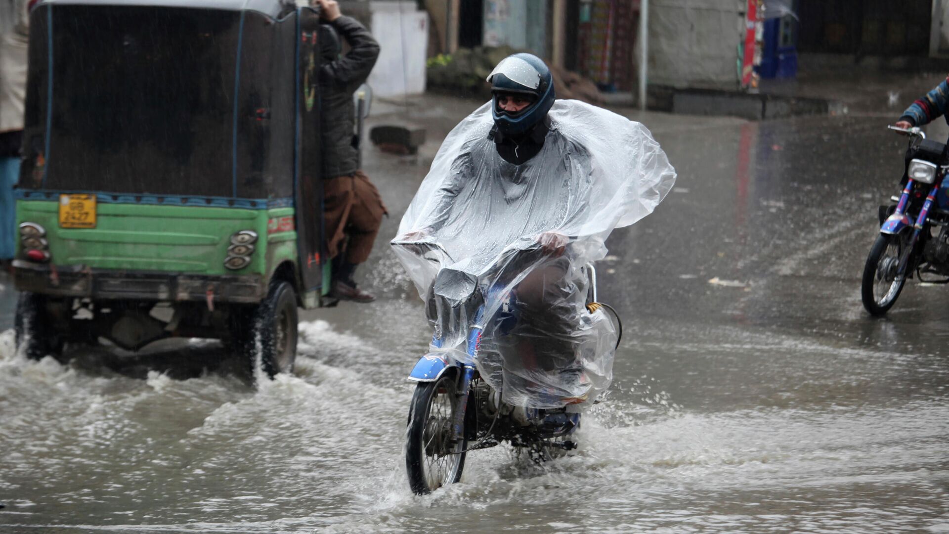 Мужчина едет на мотоцикле во время дождя в городе Пешавар, Пакистан - РИА Новости, 1920, 23.01.2022