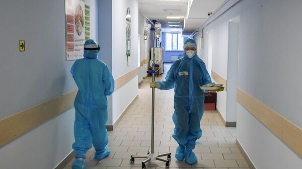 Медицинская сестра несет штатив для капельницы во временном госпитале для пациентов с Covid-19