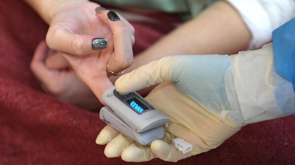 Медицинская сестра измеряет пульсометром сатурацию у пациентки
