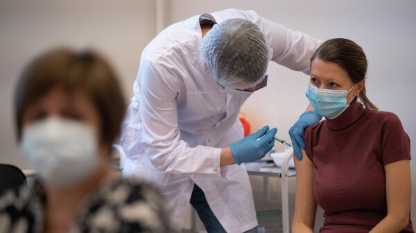 Медицинский работник делает девушке прививку от COVID-19 в центре вакцинации в ГУМе в Москве