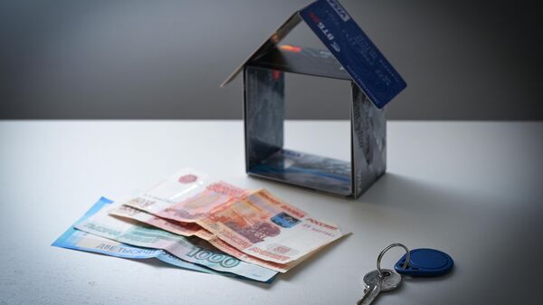 Ключ, деньги и домик, сложенный из банковских карт