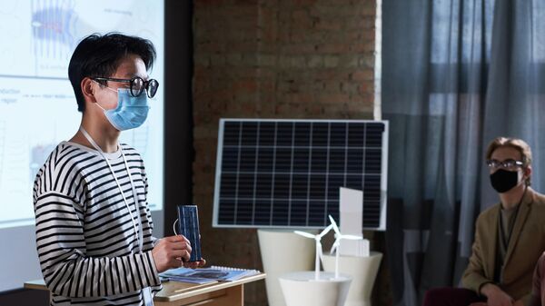 Инженер в маске с солнечной батареей в руках