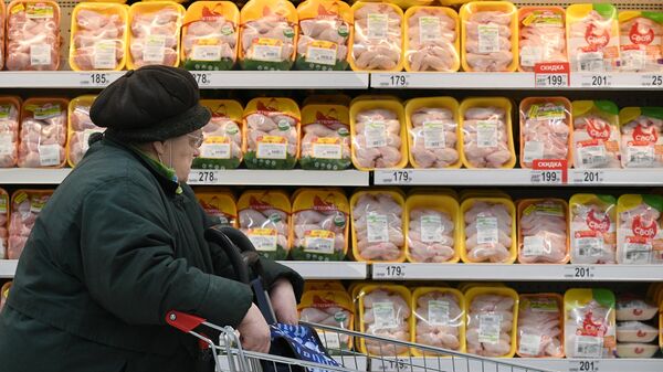 Покупательница выбирает курицу в мясном отделе в магазине в Москве 