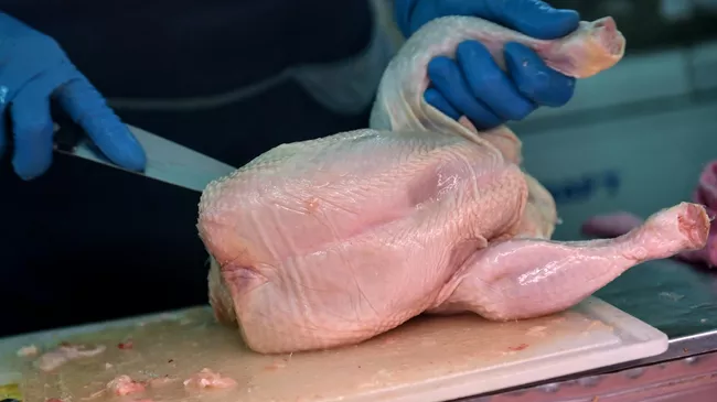 Продавец разделывает курицу на рынке в Симферополе
