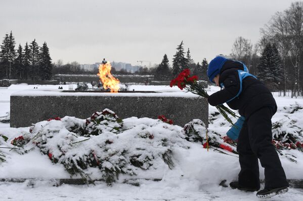 Мальчик возлагает цветы к вечному огню у монумента Мать-Родина на Пискаревском мемориальном кладбище в память о погибших в годы блокады