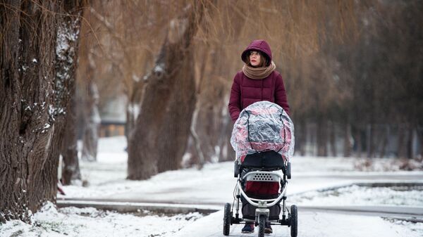 Девушка с детской коляской в парке