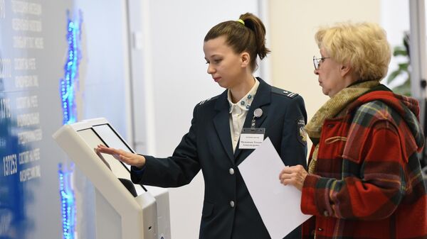 Сотрудница инспекции Федеральной налоговой службы РФ помогает посетительнице со сдачей налоговой отчетности 