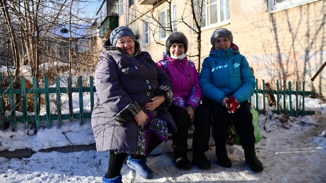 Местные жительницы сидят на лавочке возле жилого дома в Карабаше