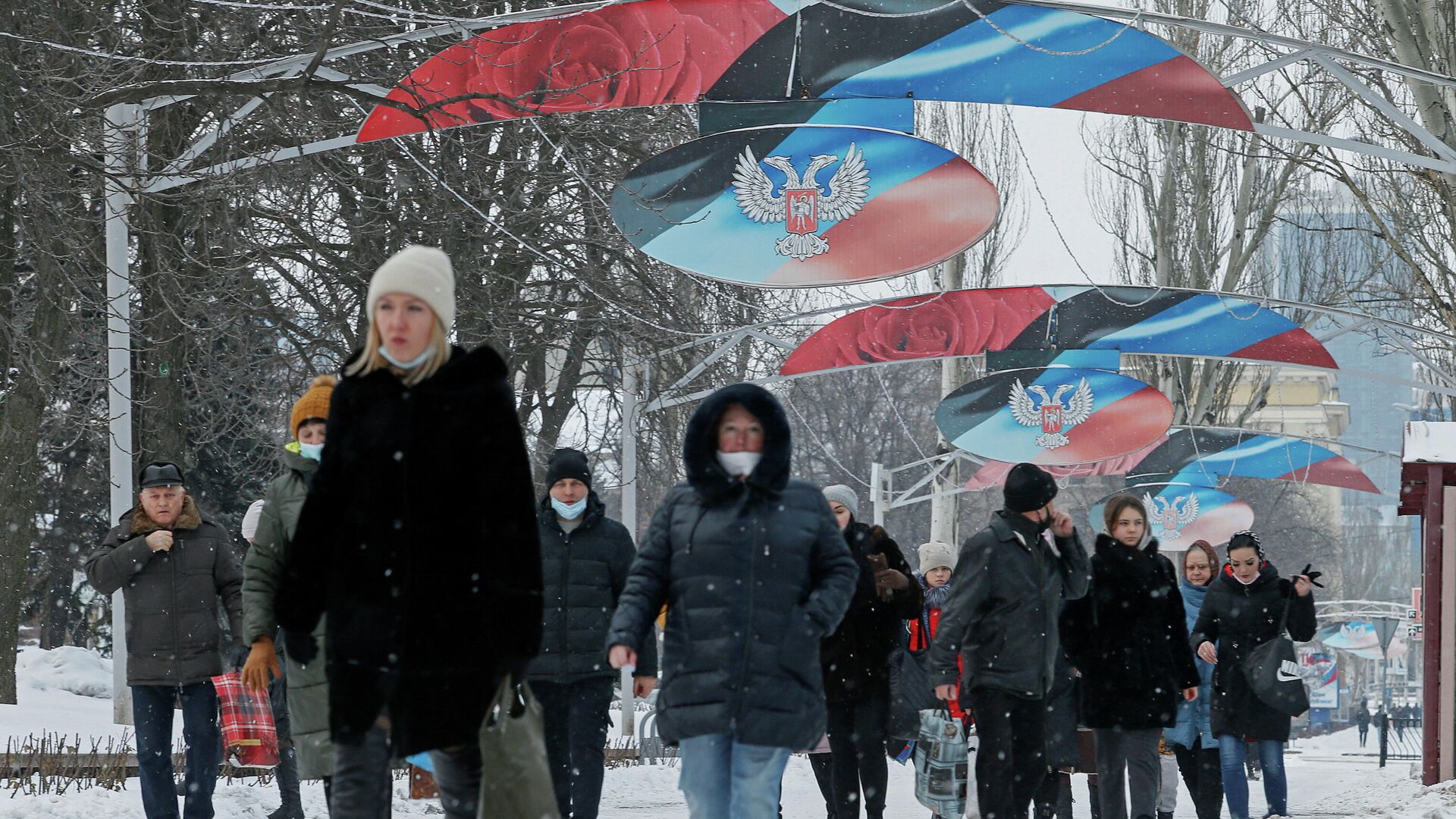Люди проходят мимо флага и герба ДНР в Донецке - РИА Новости, 1920, 10.02.2022