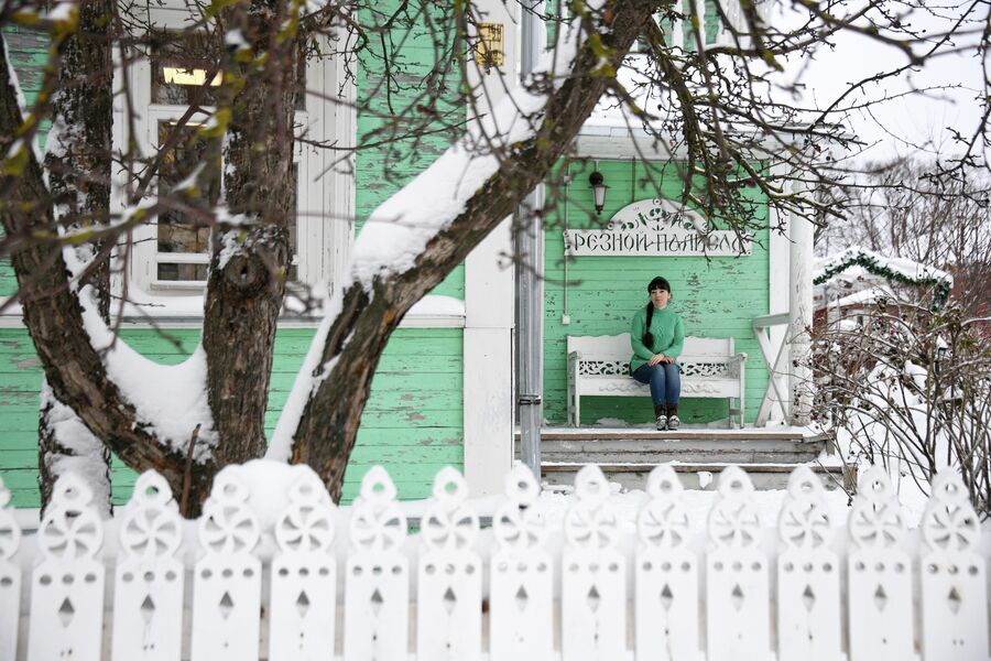 Посетительница на скамейке у входа в здание Центра народных художественных промыслов и ремесел Резной Палисад  в Вологде
