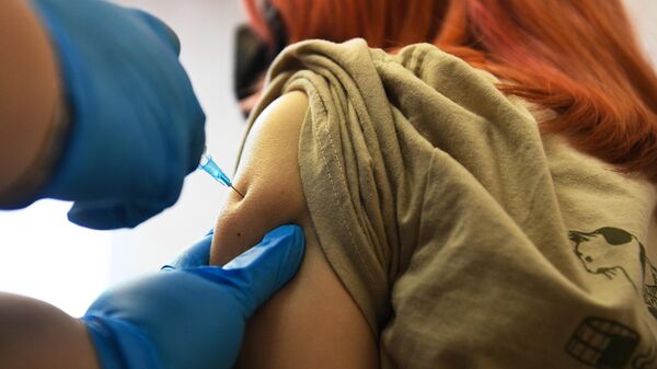 Медицинская сестра проводит вакцинацию подростка вакциной Гам-КОВИД-Вак-М (Спутник М)