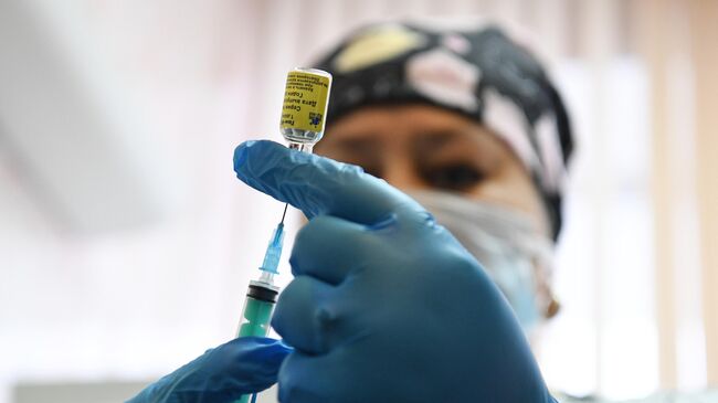 Медицинская сестра набирает в шприц вакцину