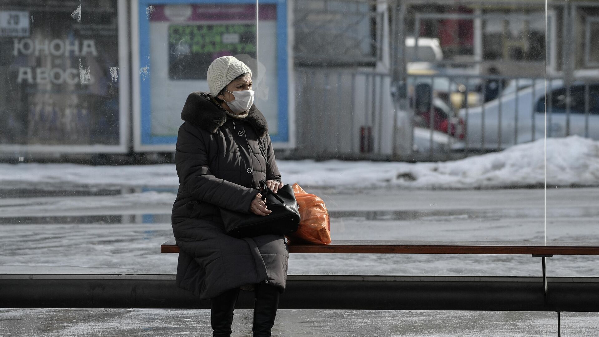 Пожилая женщина в защитной маске на остановке общественного транспорта в Симферополе - РИА Новости, 1920, 06.02.2022