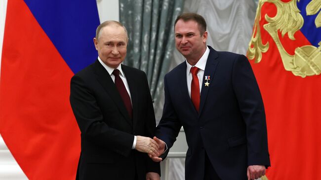 Президент России Владимир Путин и летчик-испытатель Евгений Крутов, награжденный Звездой Героя Российской Федерации, на церемонии вручения государственных наград в Екатерининском зале Кремля. 2 февраля 2022