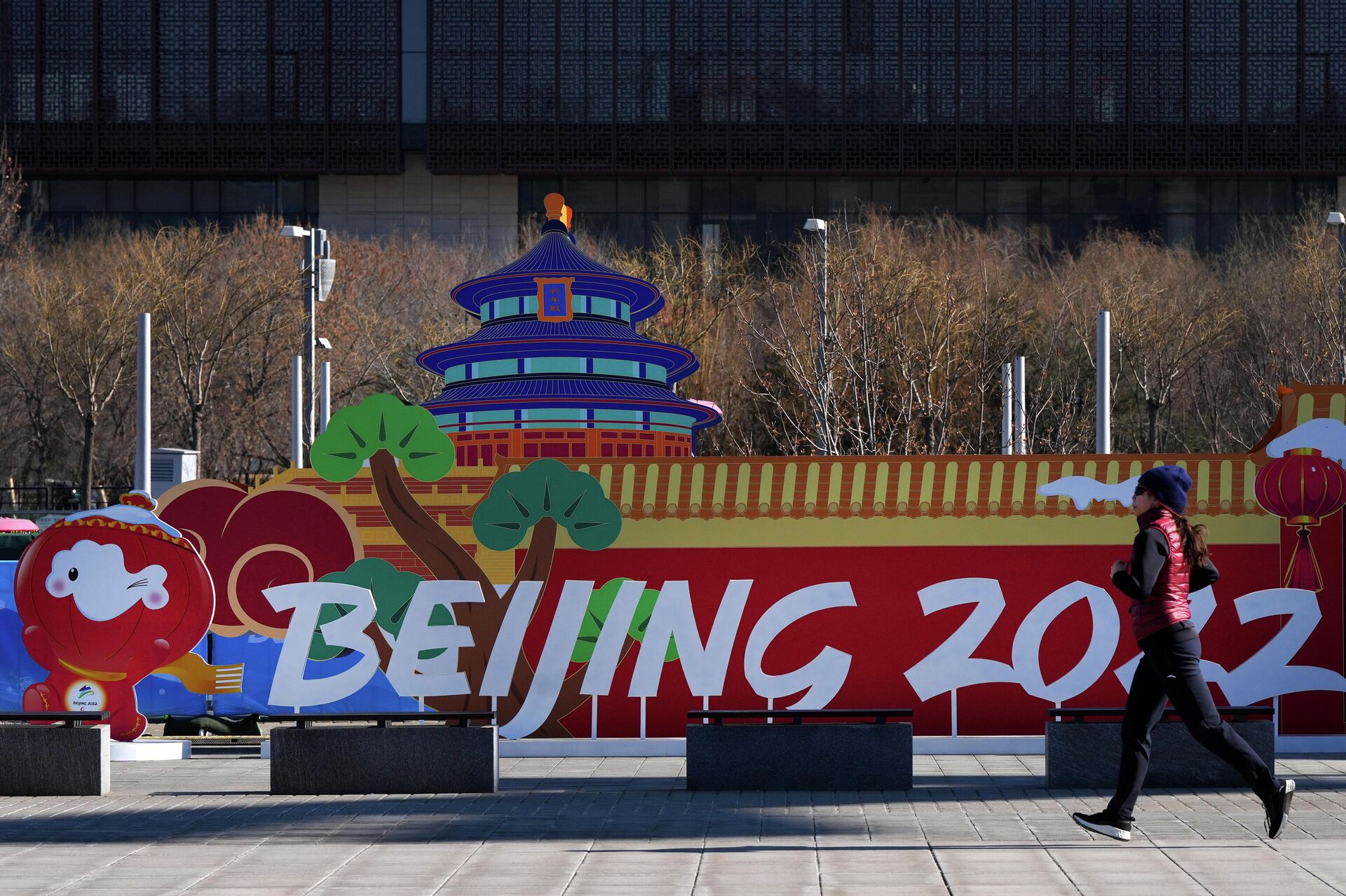 Девушка пробегает у инсталляции с символикой зимних Олимпийских игр 2022 в парке возле главного пресс-центра игр в Пекине - РИА Новости, 1920, 04.02.2022