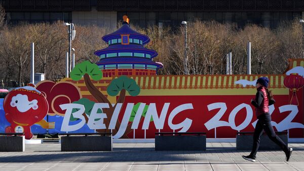 Девушка пробегает у инсталляции с символикой зимних Олимпийских игр 2022 в парке возле главного пресс-центра игр в Пекине